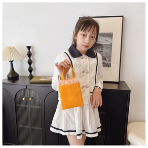 Close-up of bright orange canvas girls' handbag featuring delicate white lace trim details