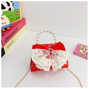 Detailed shot of red child handbag with lace bow, pearl handle, and golden metal chain