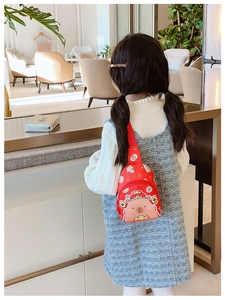 Vue arrière d'un enfant portant un sac bandoulière rouge avec imprimé capybara mignon