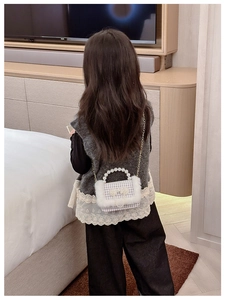 Détail du sac enfant avec poignée en perles, texture peluche à carreaux et chaîne dorée
