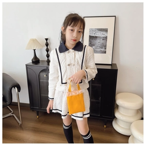 Detail of bright orange lace-trimmed handbag paired with waffle-knit girl's outfit
