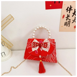 Detail of red Chinese style kid purse with embroidery, bow, tassel and pearl handle