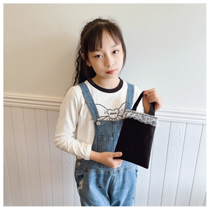 Detail of small black fabric girls handbag featuring elegant white lace trim on top