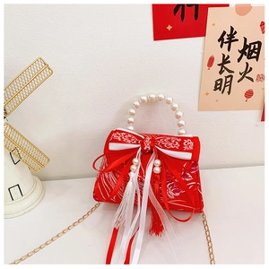 Detail of red Chinese style girls handbag with embroidery pearl handle and festive bow