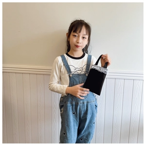 Close-up of small black canvas handbag for girls with elegant white lace trim detail