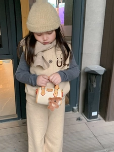 Dettaglio di una mini borsa Boston bianca con manici marroni e ciondolo a forma di orsetto