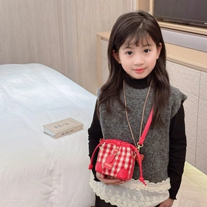 Girl wearing a red and white checkered crossbody bag with red leather strap in a bedroom