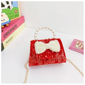 Detail of red sequined kids handbag featuring pearl bow and handle with gold chain
