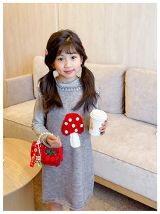 Detailed view of red sequin handbag with cute charm on a grey knit girls dress