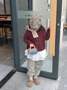 Bimba con berretto leopardato e cardigan in maglia con sciarpa beige all'aperto