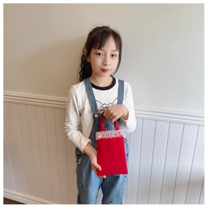 Detail of red toddler handbag featuring delicate white lace trim and durable canvas fabric
