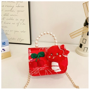 Detail of red festive children bag with pearl handle and plush snake decoration
