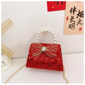 Detail of red sequin girls' bag with pearl handle and golden bow for New Year