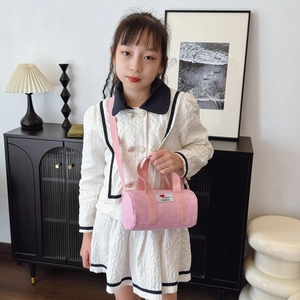 Pink canvas bucket bag for kids featuring heart patch and adjustable shoulder strap