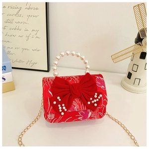 Detailed view of red velvet kids bag with pearl handle and large decorative bow