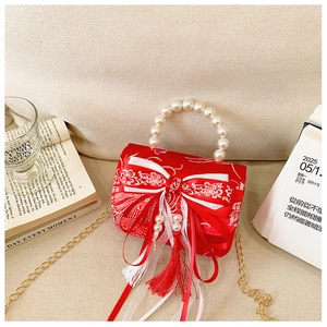 Close-up of red festive girl's bag with pearl handle and traditional bow tassel detail