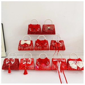 Close-up of red girls' handbags with sequins, velvet bows, and pearl handles for New Year