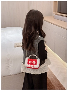 Sac enfant au crochet rouge avec bordure en fourrure blanche et poignée en perles en scène