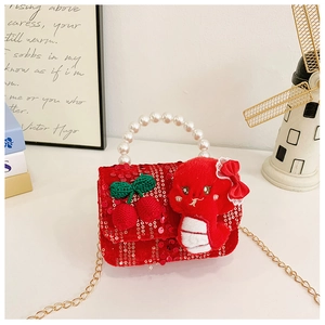 Detail of red festive sequin kids bag with pearl handle and plush cherry charm