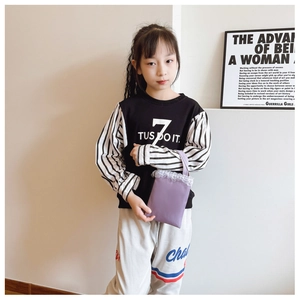 Detail of a purple lace handbag paired with a striped sweatshirt and white sports pants