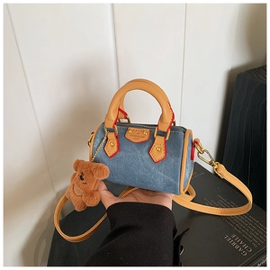 Dettaglio della mini borsa boston in denim con finiture in pelle e ciondolo orso