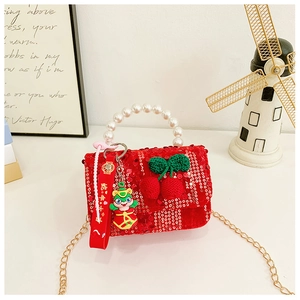 Macro detail of red sequin child purse with pearl handle and lucky snake doll charm