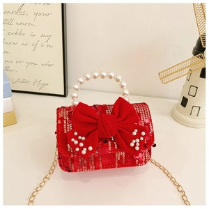 Detailed view of red sequin girl's purse with pearl handle and velvet bow detail