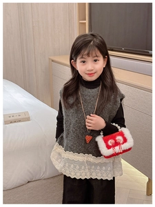 Détail du sac en peluche rouge avec poignée en perles et pendentif fraise sur tricot