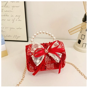 Macro detail of red sequin handbag with large white lace bow and pearl handle