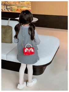 Detail of red girls handbag featuring oversized bow and elegant pearl handle straps