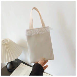 Close-up of white mini girl's handbag with lace trim and woven handles in a cozy setting