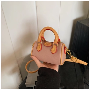 Dettaglio della mini borsa a cilindro in pelle rosa e marrone con finiture metalliche dorate