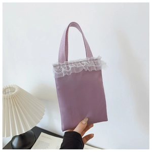 Detail of lavender fabric handbag featuring delicate white lace trim and woven handle