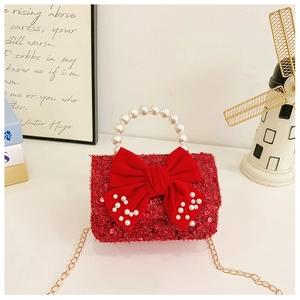 Detail of red sequined girls bag featuring a pearl handle and ornate bow embellishment