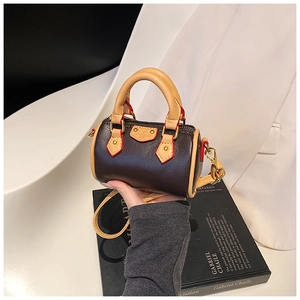 Dettaglio mini borsa a cilindro con trama litchi marrone e bordo rosso