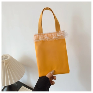 Detail view of ginger yellow girls handbag with white lace trim and thick fabric handle