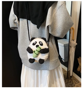 Detail of handmade crochet panda crossbody bag with metallic clasp closure and long strap
