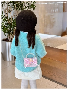 Detail showing pink bow and princess doll decoration on elegant girl's chain bag