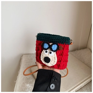 Detail of hand-knitted cartoon crossbody bag featuring red and green stitching textures