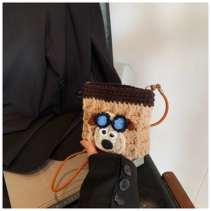 Close-up of handmade crochet puppy bag with cartoon goggles and orange shoulder strap