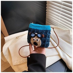 Close-up of handmade crochet puppy bag with blue yarn and premium leather strap detail