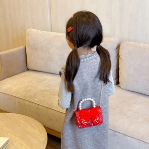 Red sequin girl's crossbody bag with large bow, pearl handle, and metal chain strap