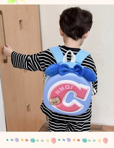 Blue kids backpack with pink C letter and cute bow shown on a child model