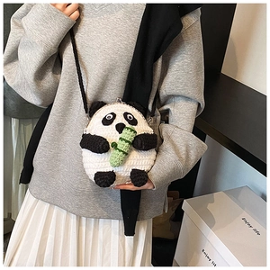 Macro detail of hand-crocheted panda crossbody bag with metal clasp and green bamboo accent