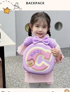 Detail of sweet pink EVA hardshell kids backpack with purple plush bow and bear charm
