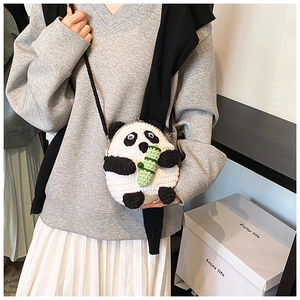 Detail of a handmade crochet panda crossbody bag with metallic clasp and black shoulder strap