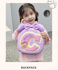 Detail of cute purple bow and soft bear badge on child's hard shell school backpack