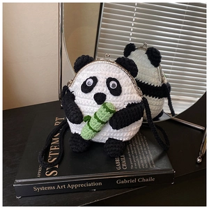 Detail of handmade crochet panda purse with metal clasp on a book with mirror reflection