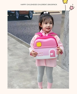 Pink house-shaped kids backpack with Sunny Day text shown on a young girl outdoors