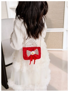 Detail of red tweed girl bag with pearl handle and mesh bow on a child model